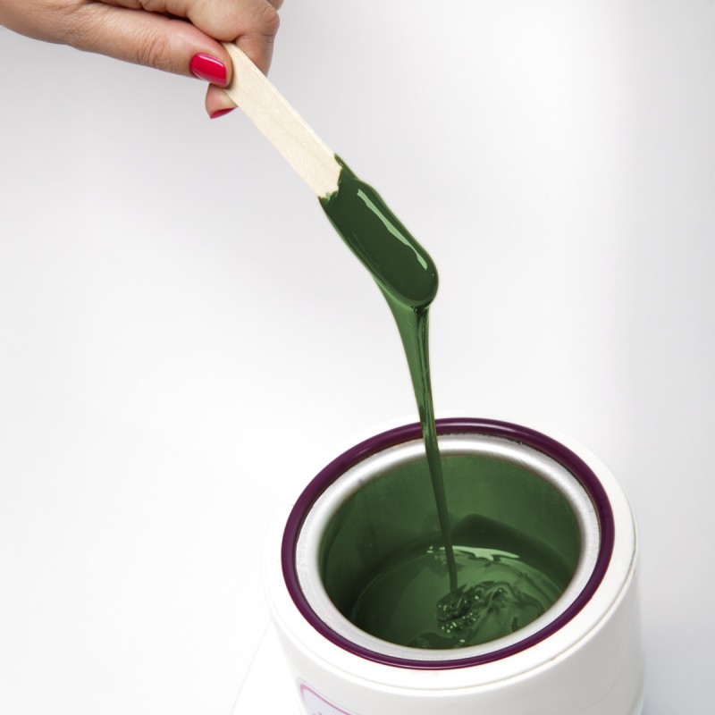 Cire traditionnelle fondue dans un chauffe-cire, spatule en bois